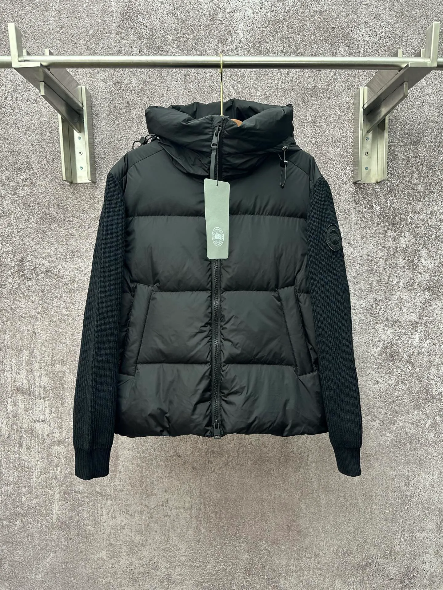 P930 Canada Goose Armband Hooded Down Jacket Fabric selection: The use of high-quality protective nylon fabric not only enhances the wear resistance of the surface, but also takes into account wind resistance, ensuring excellent performance in various harsh weather conditions.  90 national standard high-quality white duck down: selected high-loft down, weighing 170g, light and warm, with excellent temperature locking performance and good resilience.  Three-dimensional quilting process: Precision thread reinforcement to prevent velvet drilling and ensure that the fluffy and resilient elasticity lasts as new.  7-needle medium-thick knitted structure: Use thicker yarns to knit woolen fabrics with obvious thickness and weight. The texture is clearly visible and has a rough, retro texture. It has a good skeleton feel, is relatively stiff, and can maintain the silhouette of clothing for a long time. It also provides more layers of still air to lock in heat.  There is a brand exclusive LOGO on the woolen sleeve arms. It is dark and not obvious in the photo.  Accessories: One-to-one customized logo, one-to-one customized zipper pendant, one-to-one customized snap button SIZE: S M L XL